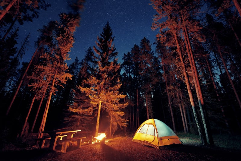Camping at night in a tent by the light of a fire