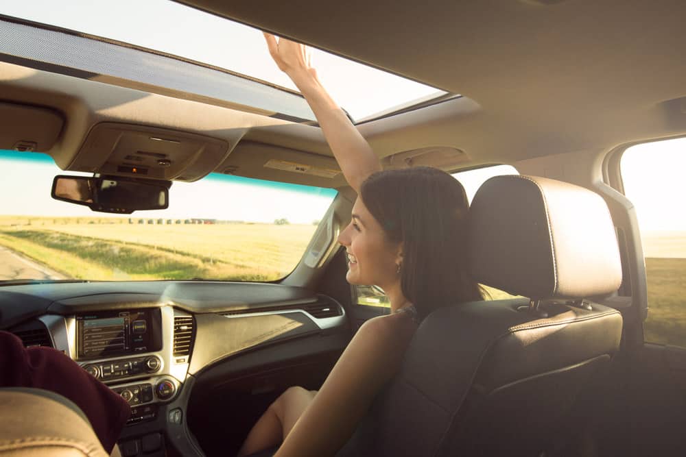 A girl on a road trip with her hand out the sunroof