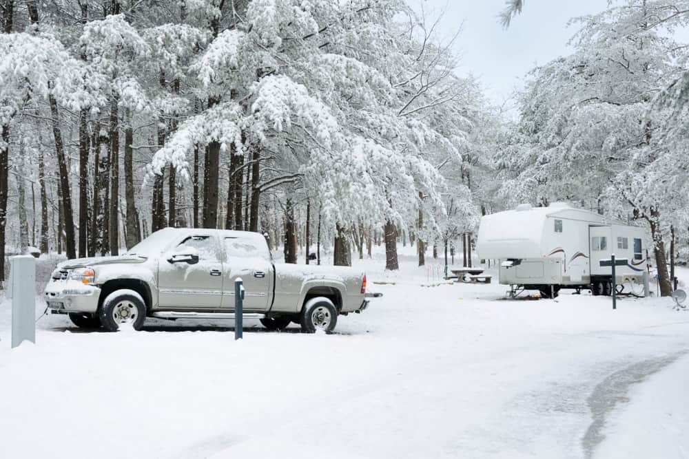 A truck and trailer at a campground in the winter.