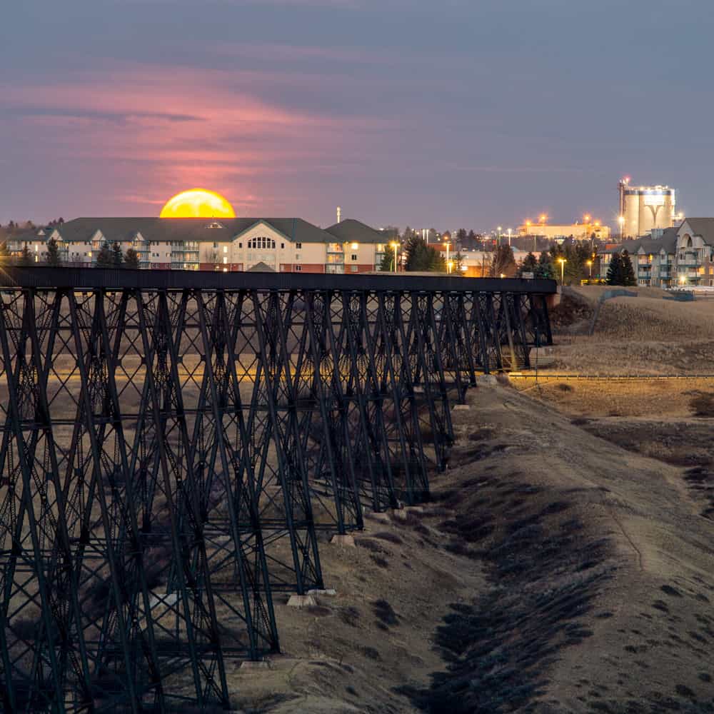 A moon rises over the Lethbridge train bridge