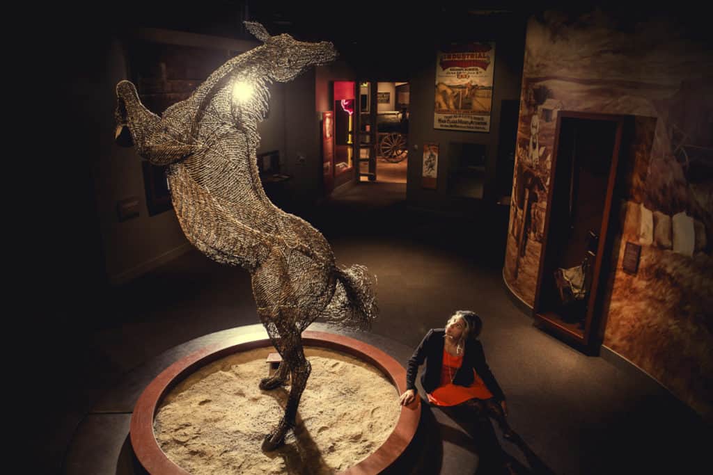 A woman looks at a horse statue in the Glenbow Museum Calgary