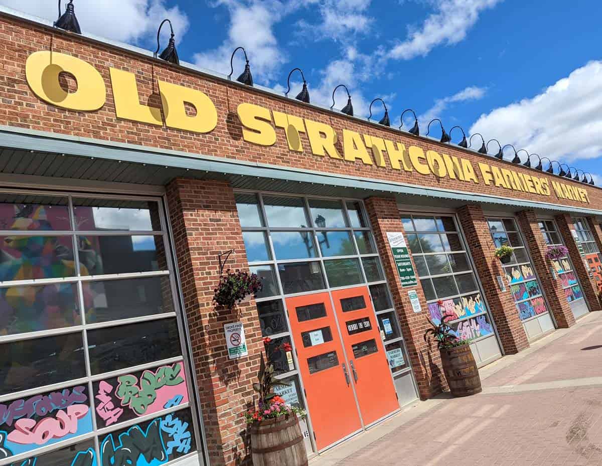 A sign that says Old Strathcona Farmer's Market against a blue sky