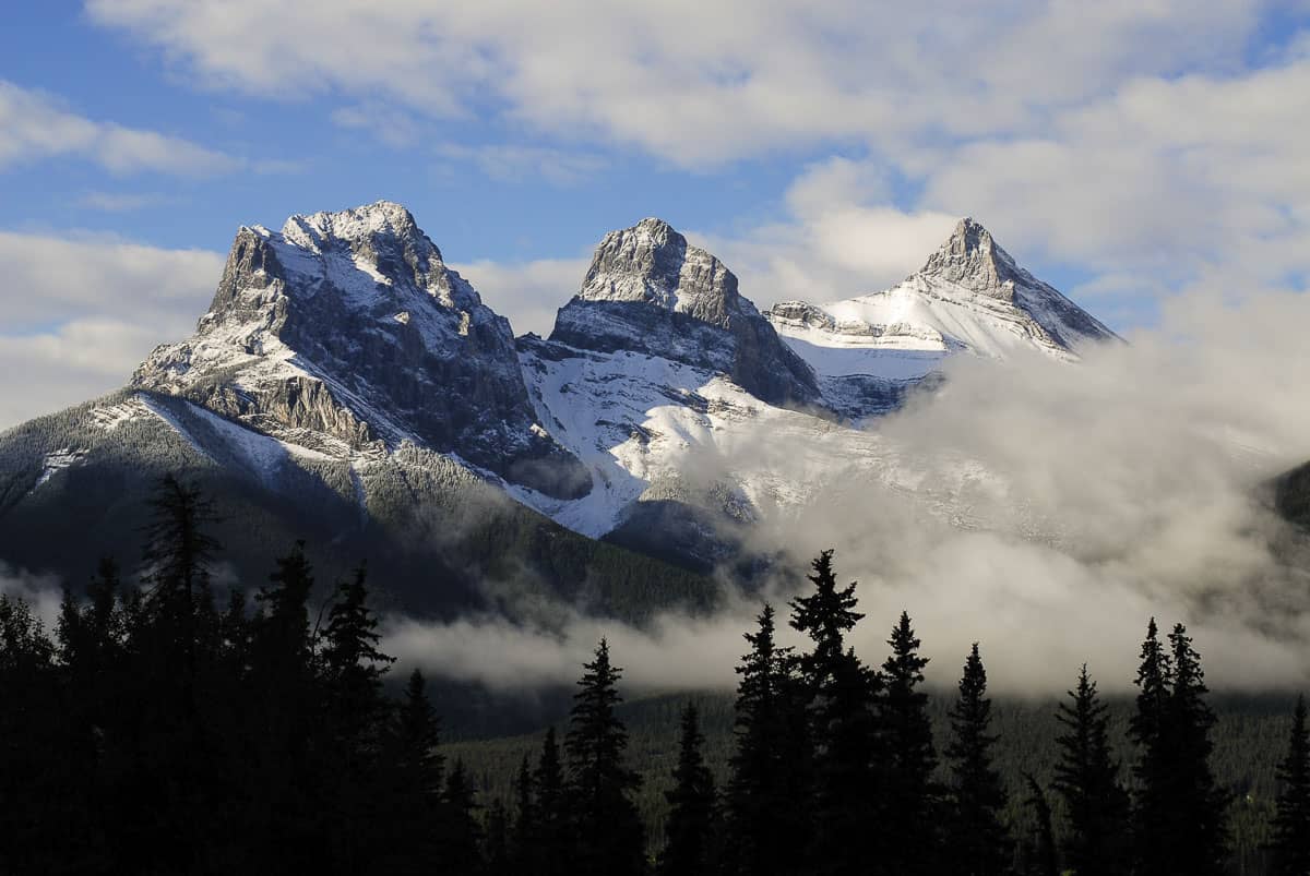 Clouds roll by the Three Sisters mountains in Canmore