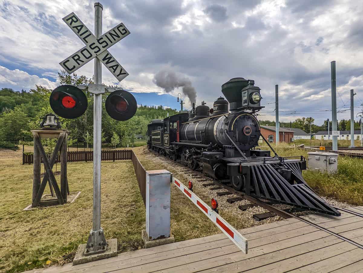 A steam train at a rail crossing in Fort Edmonton Park, Alberta