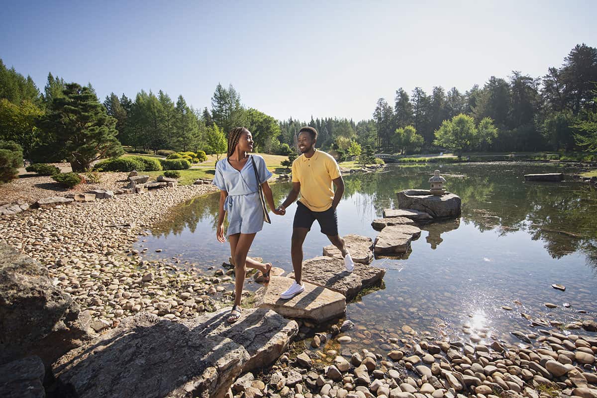 University of Alberta Botanical Garden_Couple walks on stones over pond